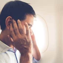 Male passenger having ear pop on the airplane while taking off (or landing)