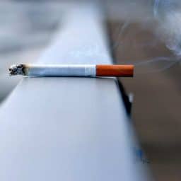 A lit cigarette on a ledge.