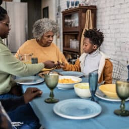 Family eating dinner together, young boy wearing hearing aid.