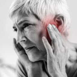 Woman holds ears, has tinnitus