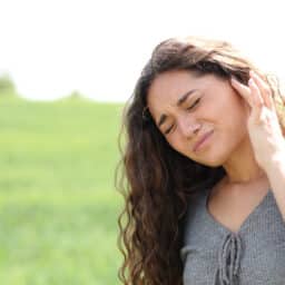 Woman with tinnitus holds ear
