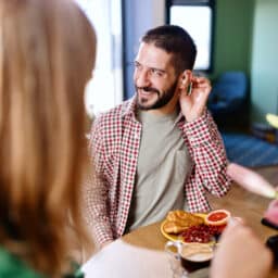 Happy man wearing hearing aids at breakfast
