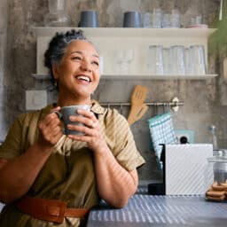 Contented woman in her kitchen drinking coffee.