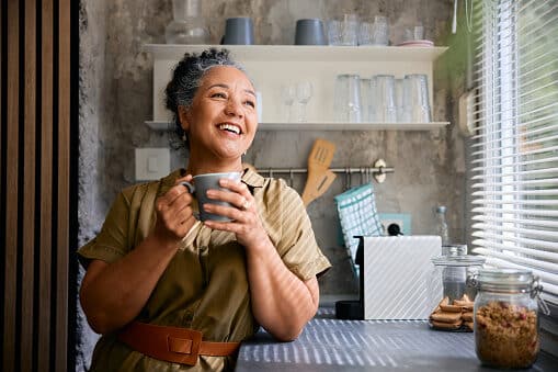 Contented woman in her kitchen drinking coffee.