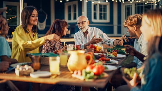 A multigenerational family gathers for a backyard barbecue on a lovely summer evening.