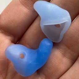 A close-up of two blue silicone custom earplugs resting in someone's hand.