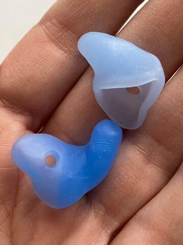 A close-up of two blue silicone custom earplugs resting in someone's hand.