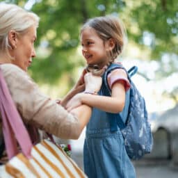 A touching moment as a mother helps her daughter get ready for school, embodying care, love, and support. Outdoors, highlighted by warm morning light and a cheerful atmosphere, this image captures family togetherness.